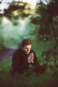 Man sitting in forest praying to God.