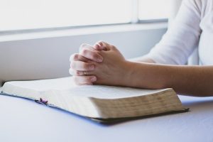 A woman praying over a bible.